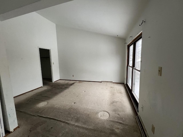 carpeted spare room featuring vaulted ceiling