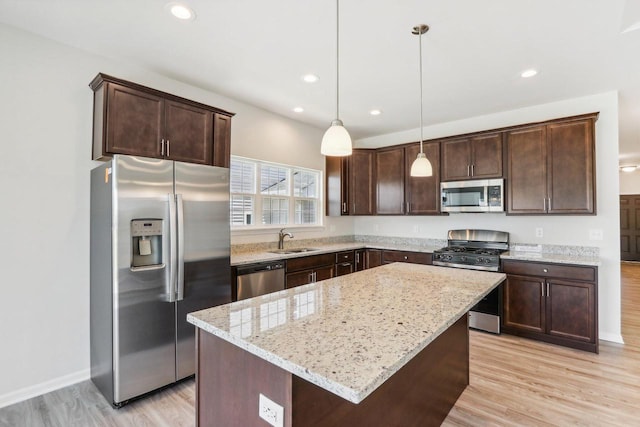 kitchen with appliances with stainless steel finishes, pendant lighting, sink, a center island, and light stone counters