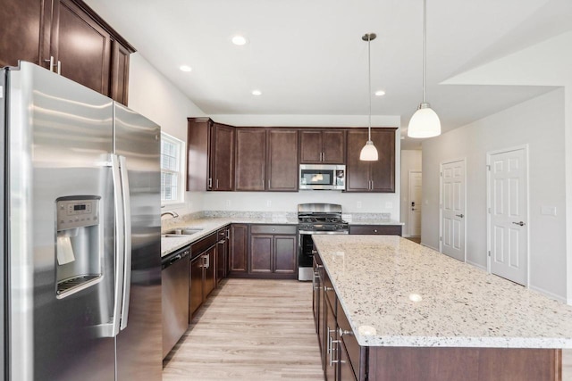 kitchen with stainless steel appliances, decorative light fixtures, a center island, and sink