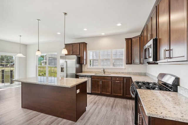 kitchen with a kitchen island, appliances with stainless steel finishes, sink, and hanging light fixtures