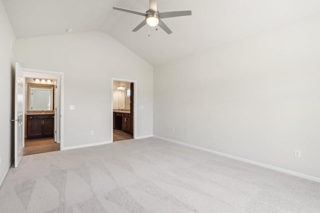 unfurnished bedroom with ensuite bathroom, lofted ceiling, light colored carpet, and ceiling fan