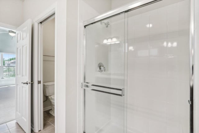 bathroom featuring tile patterned flooring, a shower with shower door, and toilet