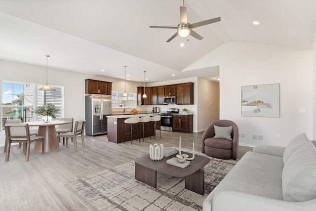 living room with vaulted ceiling, ceiling fan, and light wood-type flooring