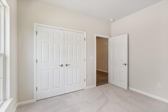 unfurnished bedroom featuring multiple windows, light colored carpet, and a closet