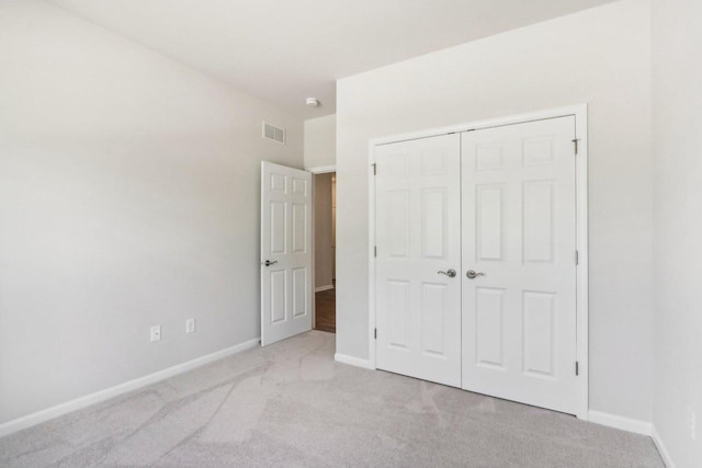 unfurnished bedroom featuring light colored carpet and a closet