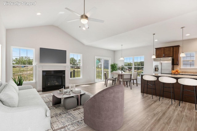 living room with ceiling fan, lofted ceiling, and light hardwood / wood-style flooring