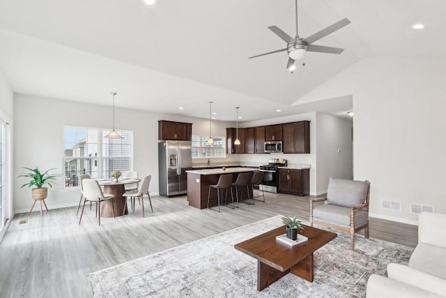 living room with vaulted ceiling, ceiling fan, and light hardwood / wood-style floors