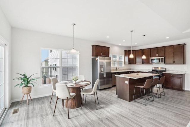 kitchen with decorative light fixtures, a breakfast bar, a center island, and appliances with stainless steel finishes