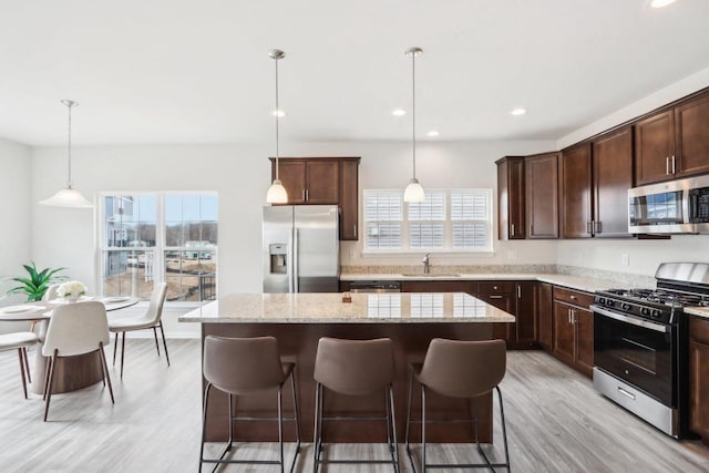 kitchen with a kitchen island, appliances with stainless steel finishes, pendant lighting, sink, and dark brown cabinets