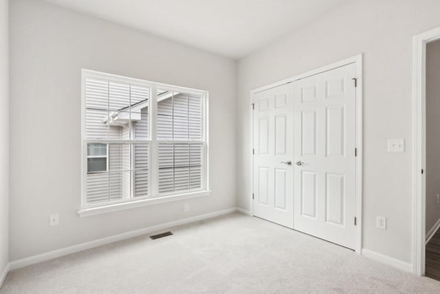 unfurnished bedroom featuring light colored carpet and a closet