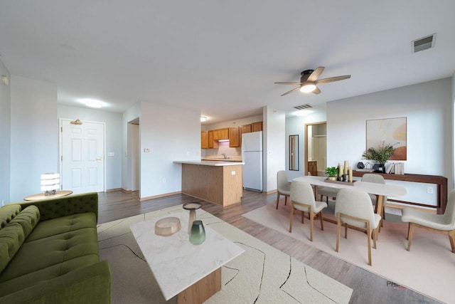 living room featuring ceiling fan, light hardwood / wood-style floors, and sink