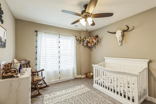 carpeted bedroom with ceiling fan and a nursery area