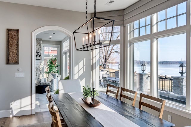 dining space featuring hardwood / wood-style flooring, a water view, and a notable chandelier