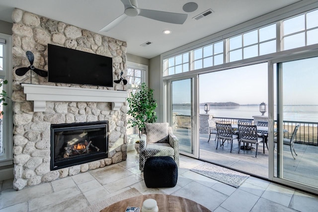 living room with ceiling fan and a stone fireplace