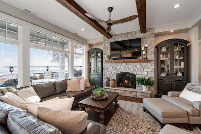 living room featuring hardwood / wood-style flooring, ceiling fan, beam ceiling, and a fireplace