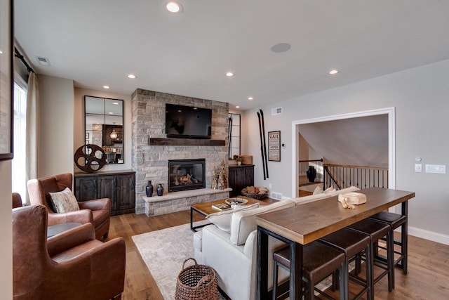 living room with a stone fireplace and light hardwood / wood-style flooring