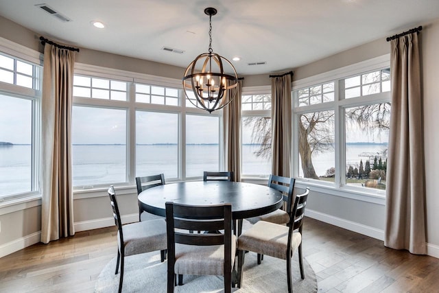 dining space featuring a chandelier, a water view, and hardwood / wood-style flooring