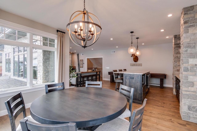 dining room with light wood-type flooring and an inviting chandelier