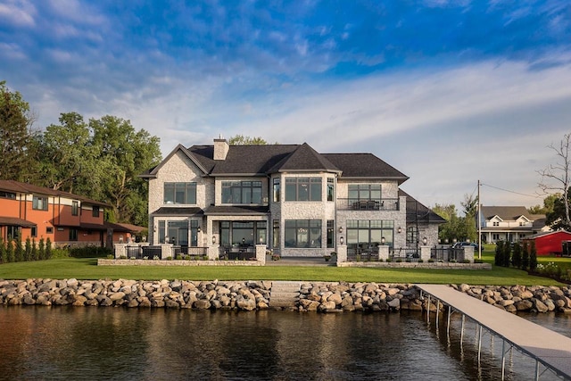 rear view of house featuring a water view and a lawn