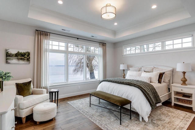 bedroom featuring wood-type flooring, a tray ceiling, and crown molding