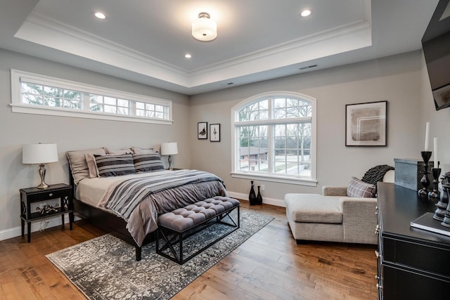 bedroom featuring a raised ceiling, wood-type flooring, and ornamental molding