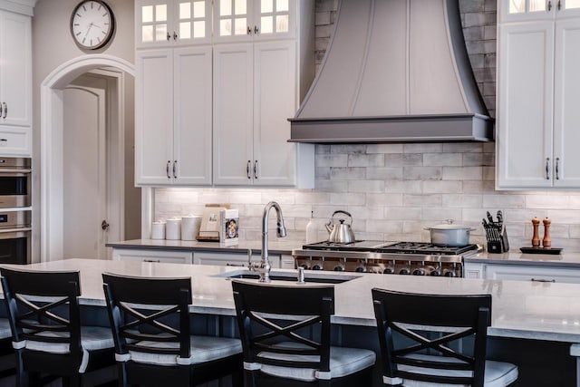 kitchen featuring white cabinets, custom range hood, and a breakfast bar area