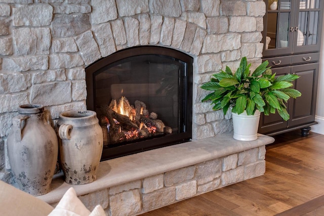 room details featuring a stone fireplace and wood-type flooring