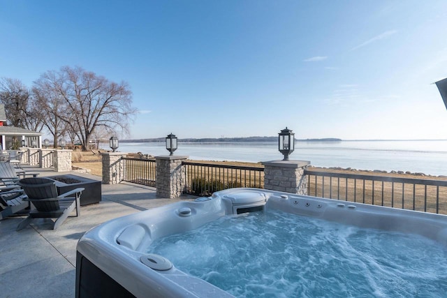 view of patio with a water view and a hot tub