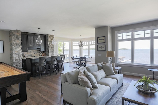 living room with dark hardwood / wood-style flooring, plenty of natural light, a water view, and an inviting chandelier