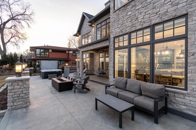 patio terrace at dusk featuring an outdoor living space with a fire pit and a hot tub