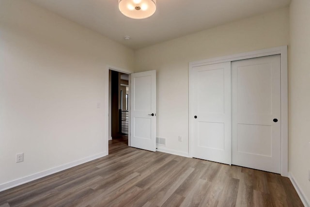 unfurnished bedroom featuring wood-type flooring and a closet