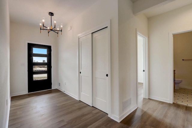 foyer entrance with wood-type flooring and a chandelier