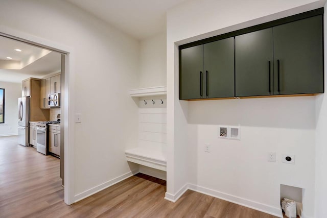 laundry room with electric dryer hookup, hookup for a washing machine, light hardwood / wood-style floors, and cabinets