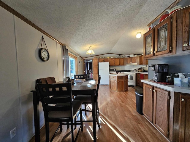 dining room featuring a textured ceiling, light hardwood / wood-style flooring, vaulted ceiling, and crown molding