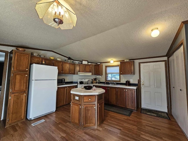 kitchen with sink, a center island, dark wood-type flooring, vaulted ceiling, and appliances with stainless steel finishes