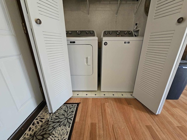 laundry room with washing machine and dryer and light hardwood / wood-style floors