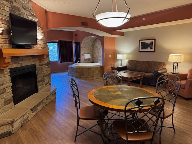 dining room with a stone fireplace and hardwood / wood-style floors