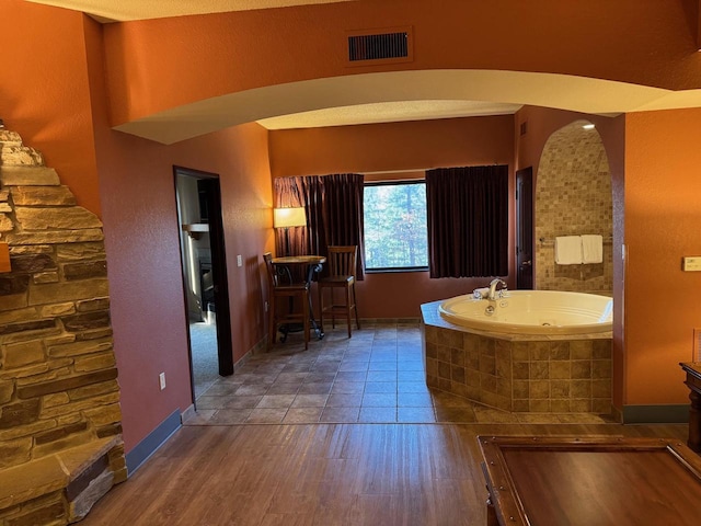 bathroom featuring vanity, wood-type flooring, and tiled tub