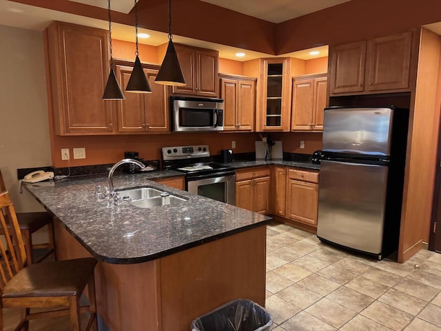 kitchen with hanging light fixtures, sink, appliances with stainless steel finishes, a kitchen bar, and kitchen peninsula