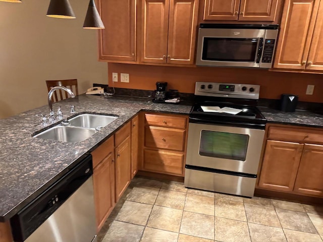 kitchen with stainless steel appliances, dark stone countertops, and sink