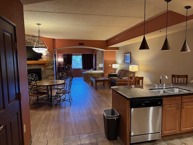 kitchen featuring pendant lighting, dishwasher, sink, dark hardwood / wood-style floors, and a fireplace