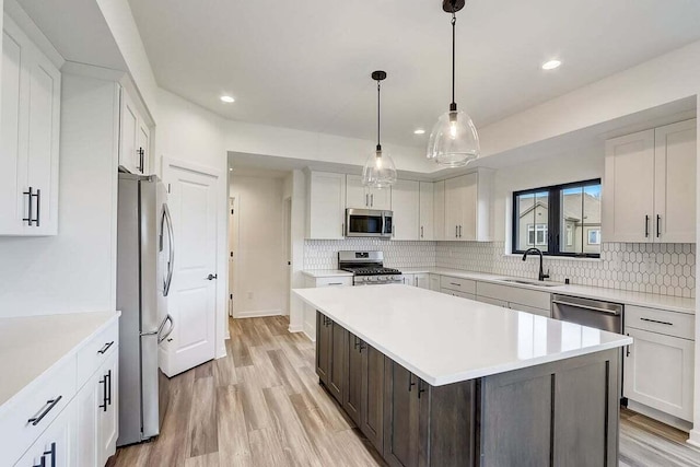 kitchen featuring sink, stainless steel appliances, a center island, and white cabinets