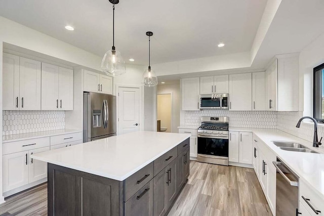 kitchen featuring sink, a center island, pendant lighting, stainless steel appliances, and white cabinets