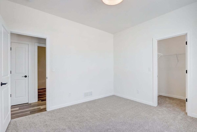 unfurnished bedroom with light colored carpet, a spacious closet, and a closet