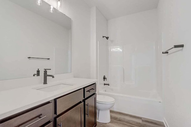 full bathroom featuring washtub / shower combination, hardwood / wood-style floors, vanity, and toilet