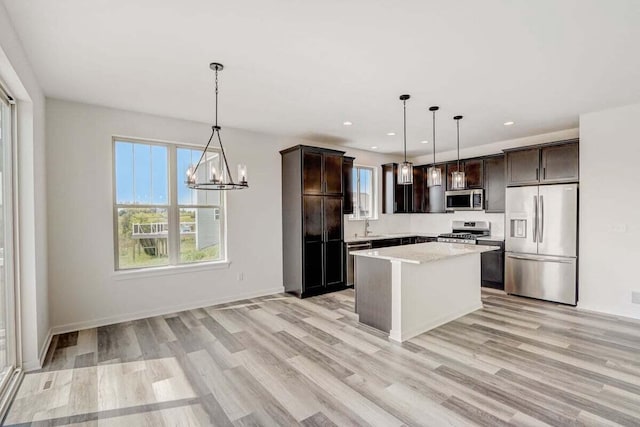 kitchen with pendant lighting, a notable chandelier, a kitchen island, and stainless steel appliances