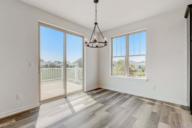 unfurnished dining area featuring light hardwood / wood-style floors and a chandelier