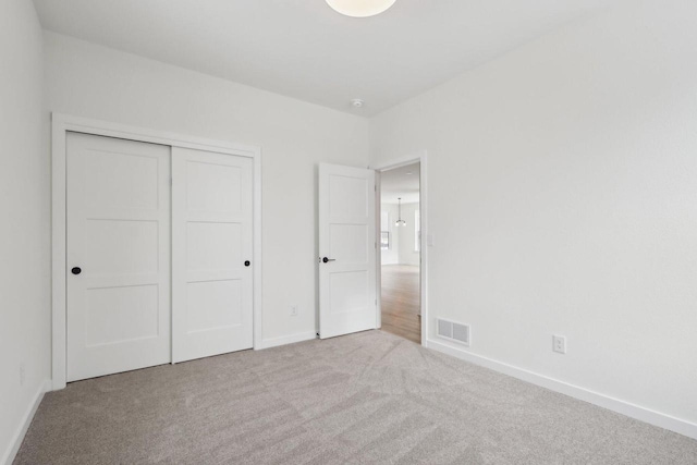 unfurnished bedroom featuring light colored carpet and a closet