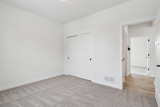 unfurnished bedroom featuring light colored carpet and a closet