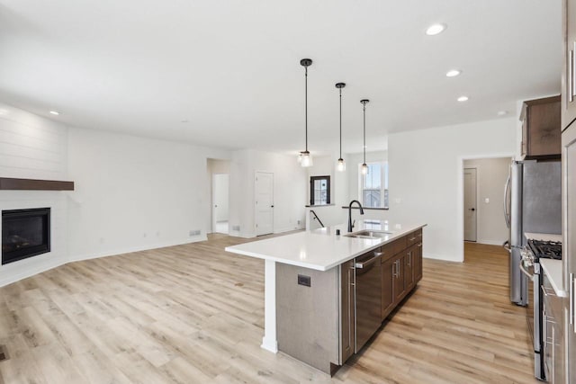 kitchen with stainless steel appliances, sink, a kitchen island with sink, and dark brown cabinets